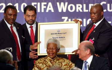 The delegation of South Africa with, Irvin Khoza, left, South Africa 2010 Bid Chairman, Danny Jordaan, 2nd from left, South Africa 2010 Bid CEO, former president Nelson Mandela, seated in center, World Football Association FIFA president Joseph Blatter, seated right, and Molefi Oliphant, right, President of the South African Football Association, show the document confirming South Africa as the host country of 2010 soccer World Cup, during an official ceremony in Zurich, Switzerland, on Saturday, May 15, 2004. FIFA's executive committee on Saturday picked South Africa ahead of Morocco and Egypt for the first World Cup to be staged in Africa. (AP Photo/Keystone, Eddy Risch)