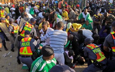 Police restrain fans prior to the warmup match between North Korea and Nigeria in Johannesburg, South Africa, Sunday June 6, 2010. Thousands of fans stampeded outside the stadium gates of a World Cup warmup game Sunday, five days before the start of soccer's showcase event. Several fans could be seen falling under the crush of people, many wearing Nigeria jerseys. Nigeria was playing North Korea at 10,000-seat Makhulong Stadium in suburban Johannesburg. (AP Photo/Frank Augstein)
