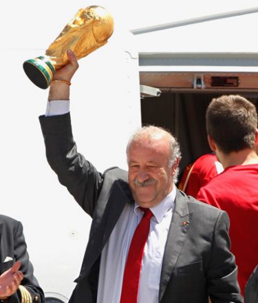 Spain's captain Iker Casillas, right, applauds as he team coach Vicente del Bosque, left, raises the World Cup trophy as they come down the plane at Madrid's Barajas airport on Monday, July 12, 2010. Spain won the World Cup after defeating the Netherlands 1-0 on Sunday. (AP Photo/Armando Franca)