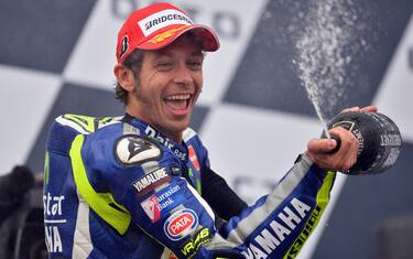 Movistar Yamaha MotoGP's Italian rider Valentino Rossi celebrates on the podium after winning the MotoGP race at the motorcycling British Grand Prix at Silverstone in Northamptonshire, England, on August 30, 2015. Valentino Rossi of Italy moved to the top of the world championship standings with his fourth victory of the season when he triumphed in the British MotoGP at Silverstone on Sunday.   AFP PHOTO / GLYN KIRK        (Photo credit should read GLYN KIRK/AFP/Getty Images)