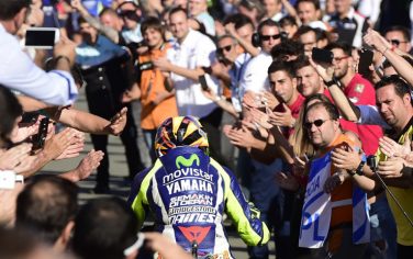 Movistar Yamaha's Italian rider Valentino Rossi is congratulated by speactators on arrival to his pit garage after the MotoGP motorcycling race at the Valencia Grand Prix at Ricardo Tormo racetrack in Cheste, near Valencia on November 8, 2015. AFP PHOTO/ JAVIER SORIANO        (Photo credit should read JAVIER SORIANO/AFP/Getty Images)
