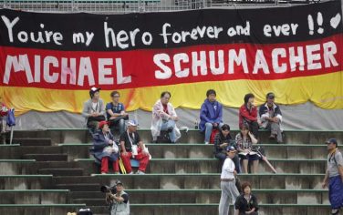 epa01883228 Spectators are seen seated on the bleachers in front of a large German national flag with with a slogan for former Formula 1 Champion Michael Schumacher of Germany during the first practice session at the Suzuka Circuit in Suzuka, Japan, 02 October 2009. The Formula One Grand Prix of Japan will take place on 04 October 2009.  EPA/Felix Heyder