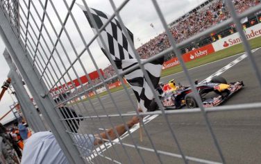 epa01768475 German Formula One driver Sebastian Vettel of Red Bull passes the finish line with checkered flag after the Grand Prix of Great Britain at the Silverstone race track in Northamptonshire, central England , 21 June 2009.  EPA/JENS BUETTNER